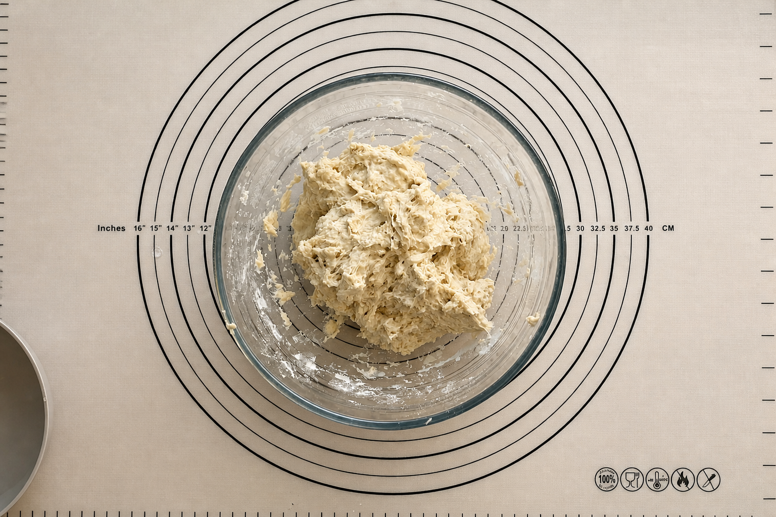Masa de pan recién mezclada, húmeda y pegajosa, dentro de un cuenco de cristal