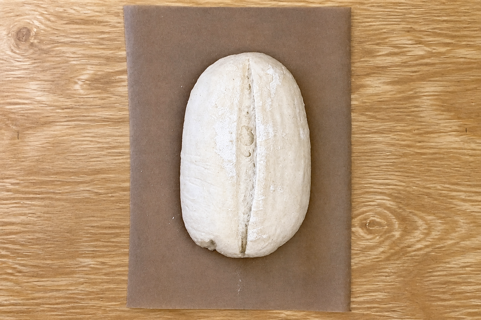 Pan formado con un corte longitudinal sobre papel de horno antes de hornearlo