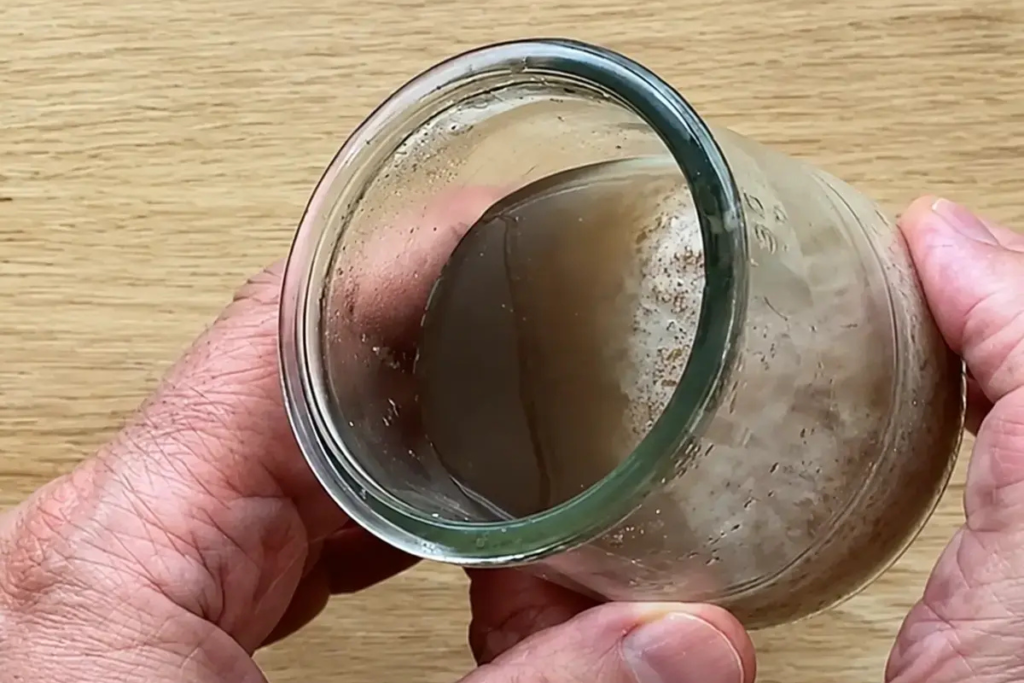 Tarro de masa madre con una capa de líquido oscuro después de varias semanas en la nevera